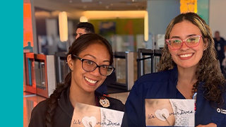 Two University Health team members holding Doctor's Day thank you cards