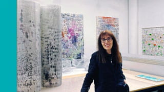 Shuli Sadé standing in front of her art