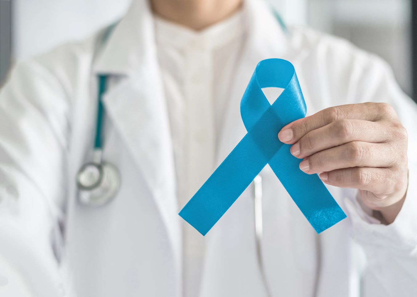Doctor in a white coat holds a blue ribbon, symbolizing prostate cancer awareness