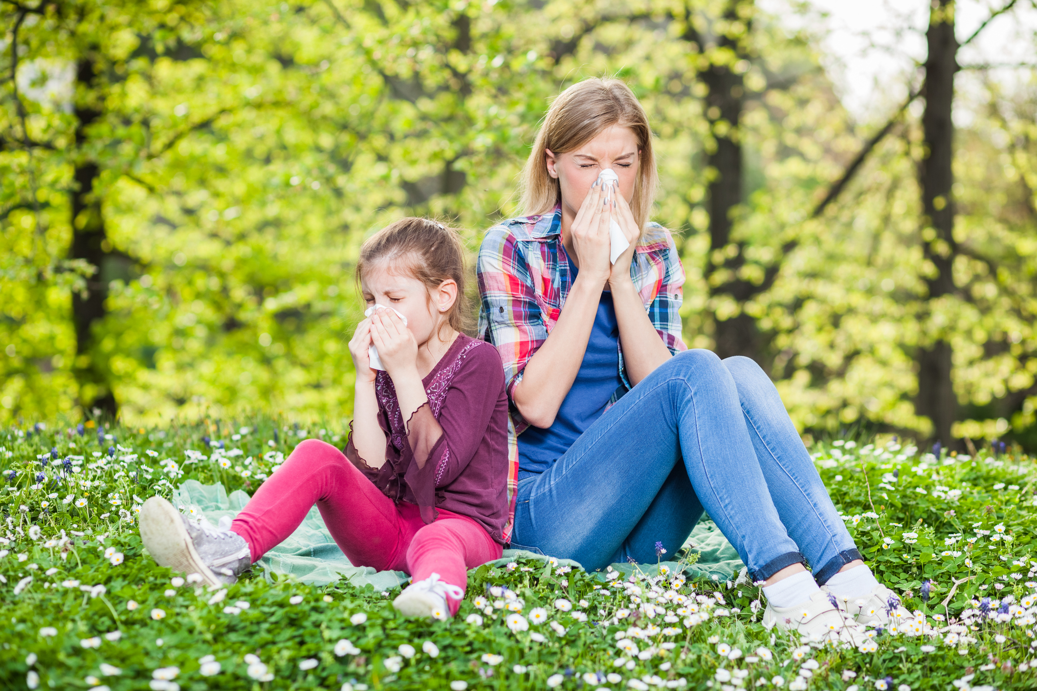 Woman and girl outside sneezing from allergies