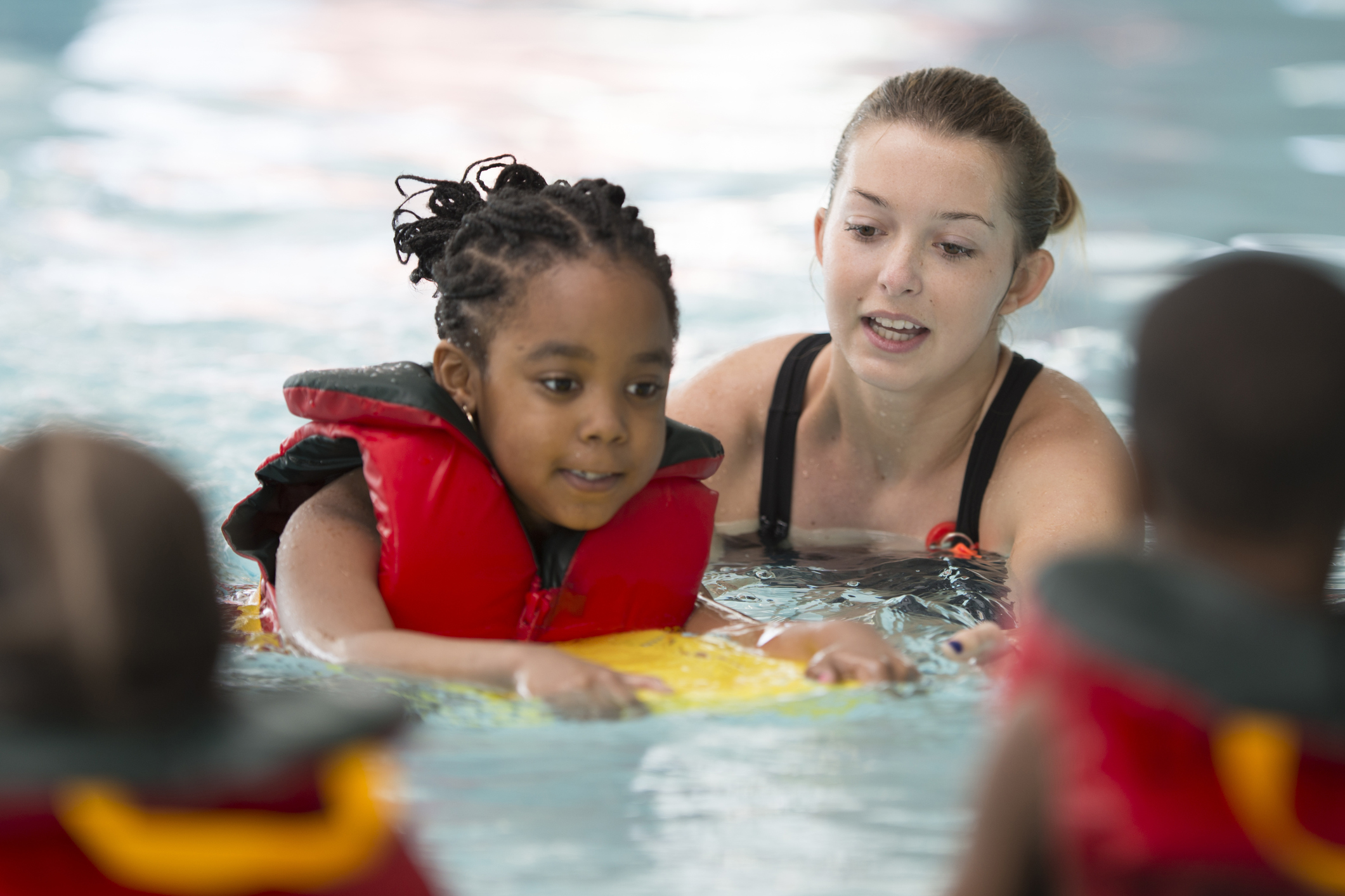 Trainer helping a child to learn how to swim in the pool