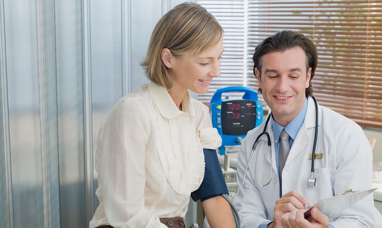 woman gets her blood pressure checked by doctor
