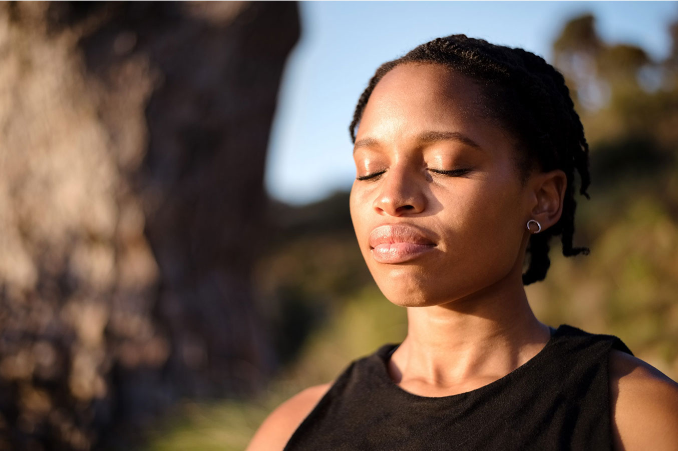 woman meditating outdoors with her eyes closed
