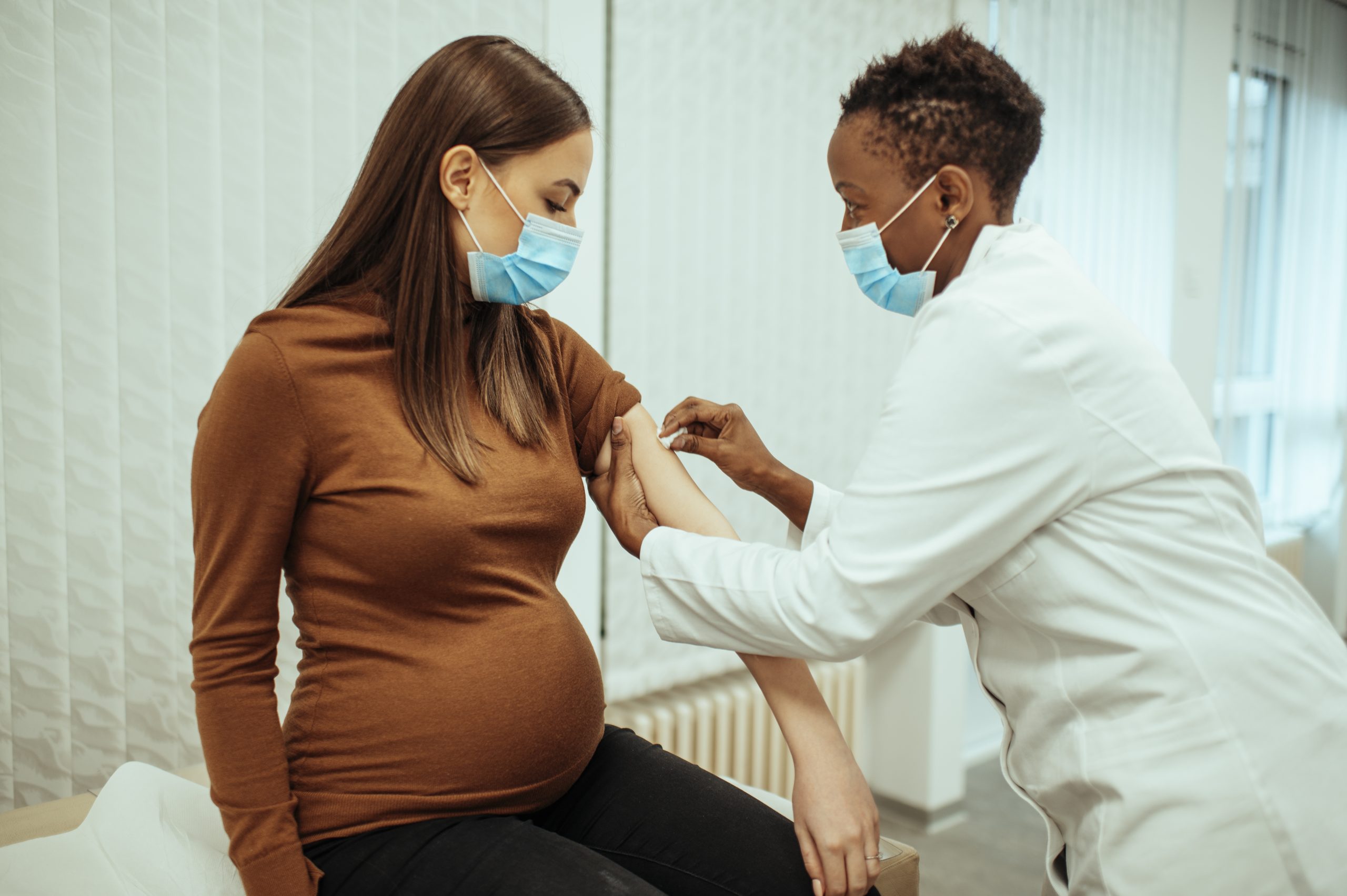 Doctor administering vaccination for a pregnant patient.