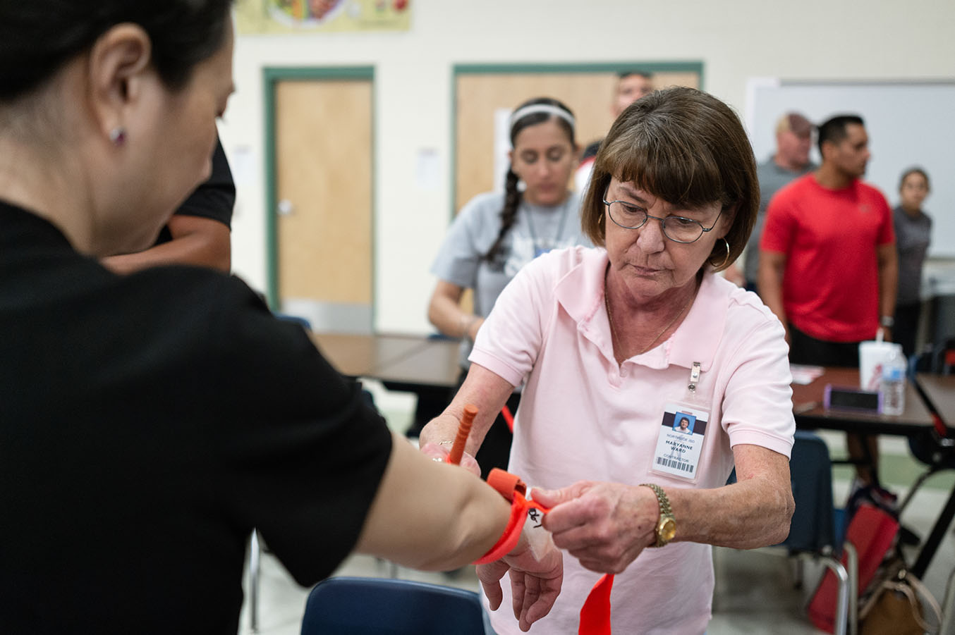 A Stop the Bleed class instructor demonstrates how to bandage an arm.