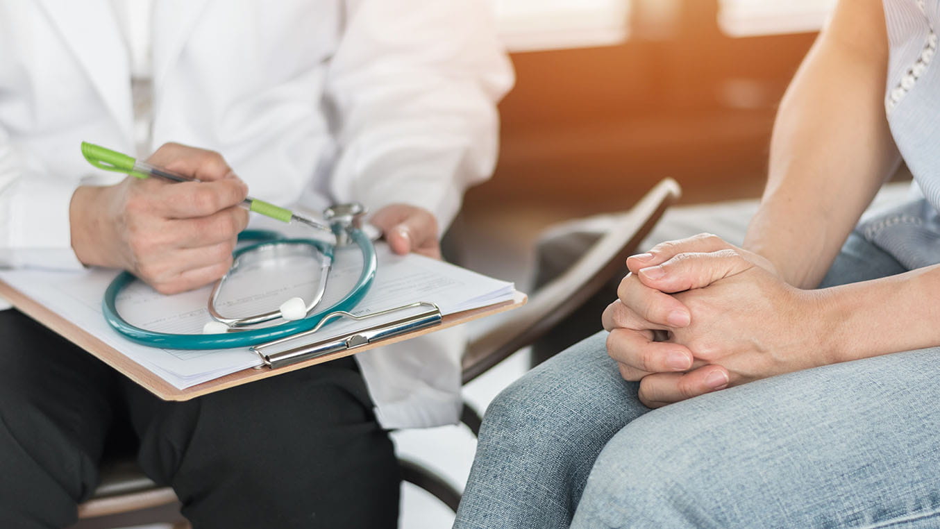 A doctor sits and speaks with a female patient.