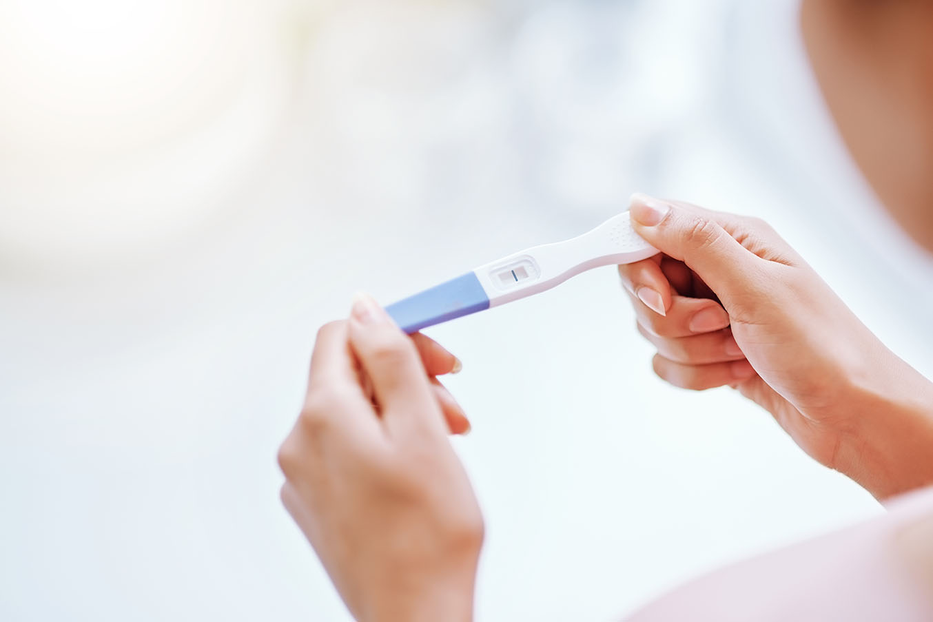 A woman looks down at a pregnancy test in her hands.