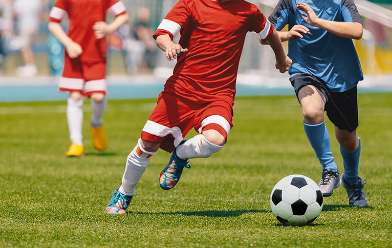 Close-up of two boys playing soccer outdoors.