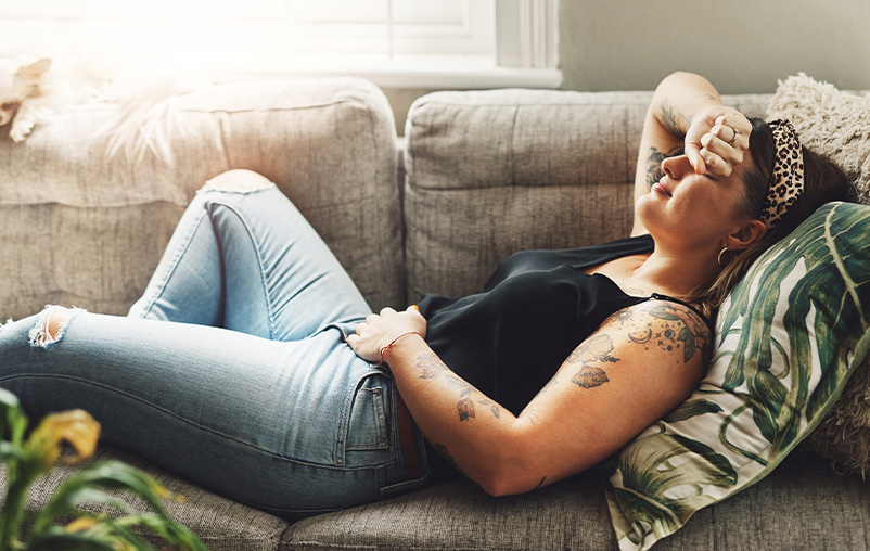 A woman reclines on a couch holding her stomach.