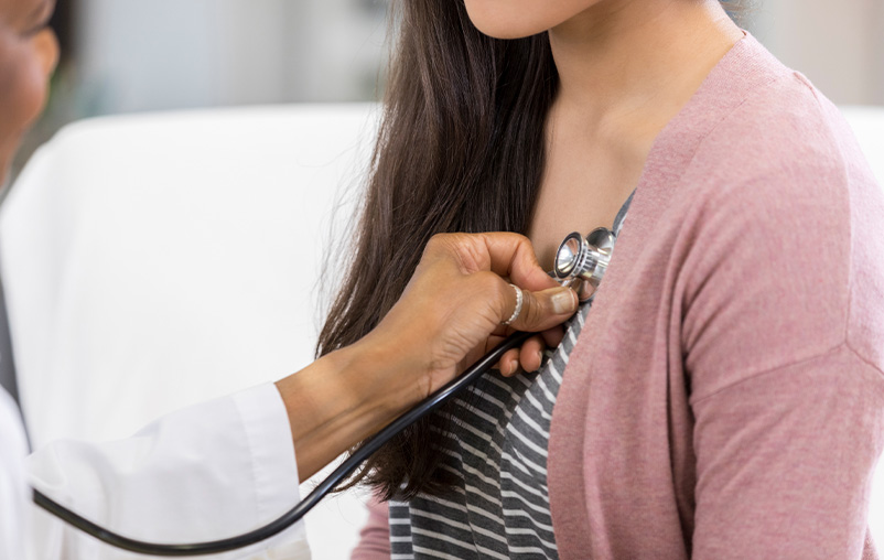 A medical provider uses a stethoscope on a woman.