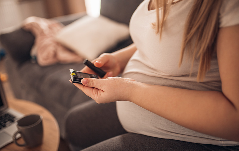A pregnant woman checks her blood sugar with a finger prick.