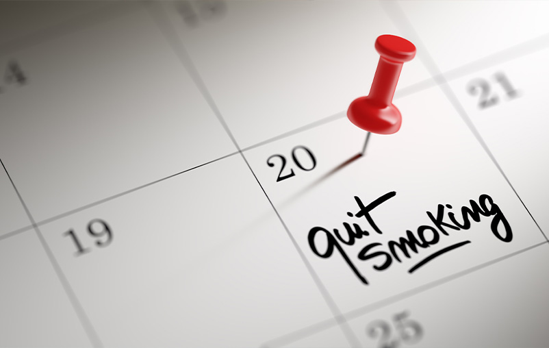 "Quit smoking" written on a calendar date with a red pushpin above it.