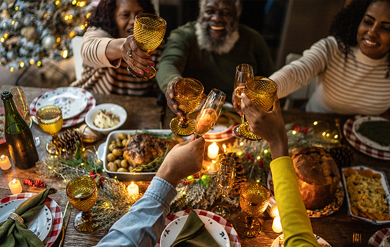 A family lifts their glasses to cheers over a cozy holiday meal.