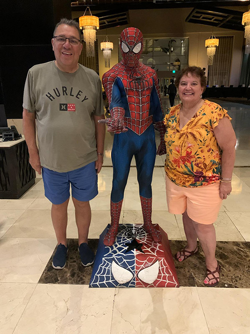 Rufino and family member pose with a statue of Spiderman.