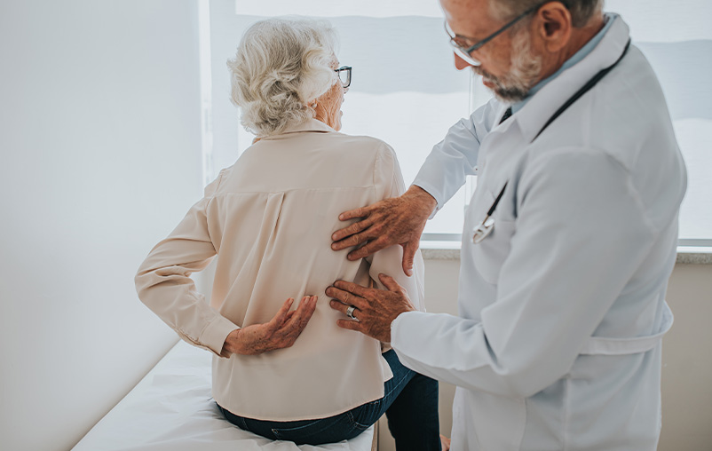 A medical provider examines a patient with back pain.