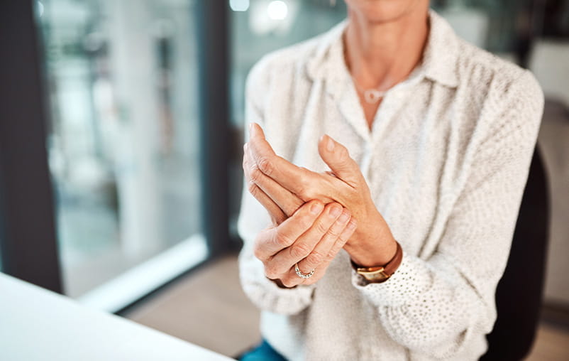 A woman holds her hand as if it's stiff.