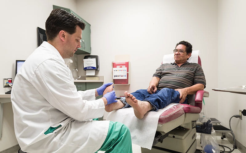 Diabetic patient having his feet checked by a provider at University Health Texas Diabetes Institute.