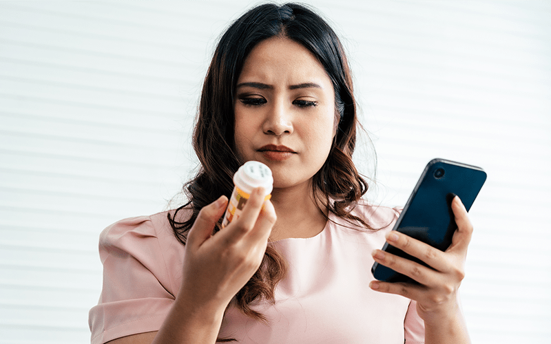 Young woman holding prescription pill bottle
