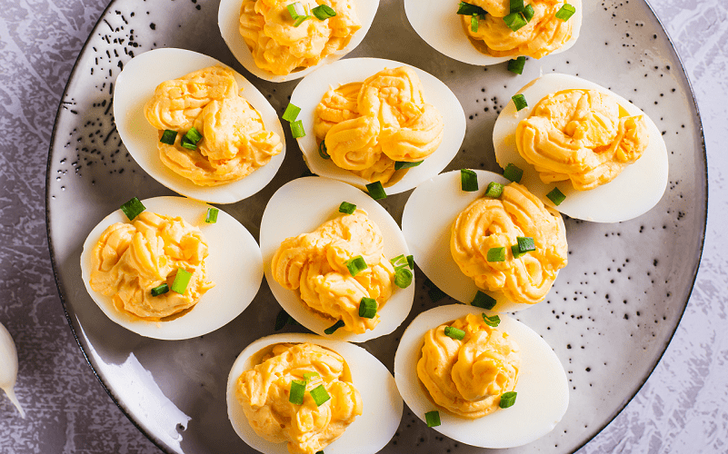 Close-up of eggs filled with a mixture of yolk, cheese and mayonnaise on a plate, top view