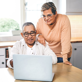 A senior couple looks at an open laptop