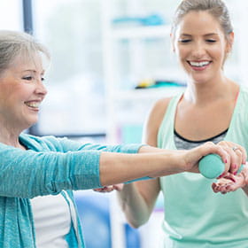 A fitness instructor shows a woman how to hold a weight.