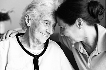 Grayscale photo of an elderly woman smiling with another young woman.