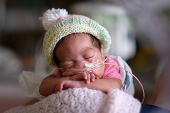 Tiny NICU baby wearing a beanie.