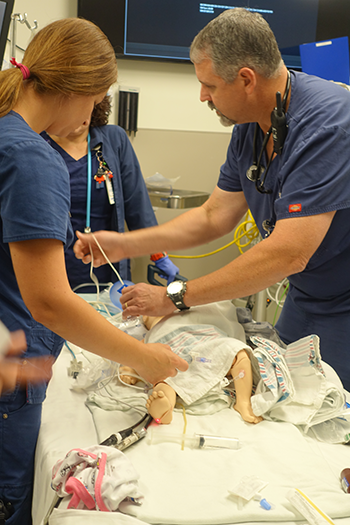Three healthcare professionals simulate a situation where they treat a pediatric patient.