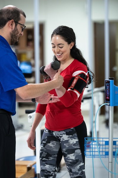 A female patient gets blood flow restriction therapy with help from a University Health therapist.