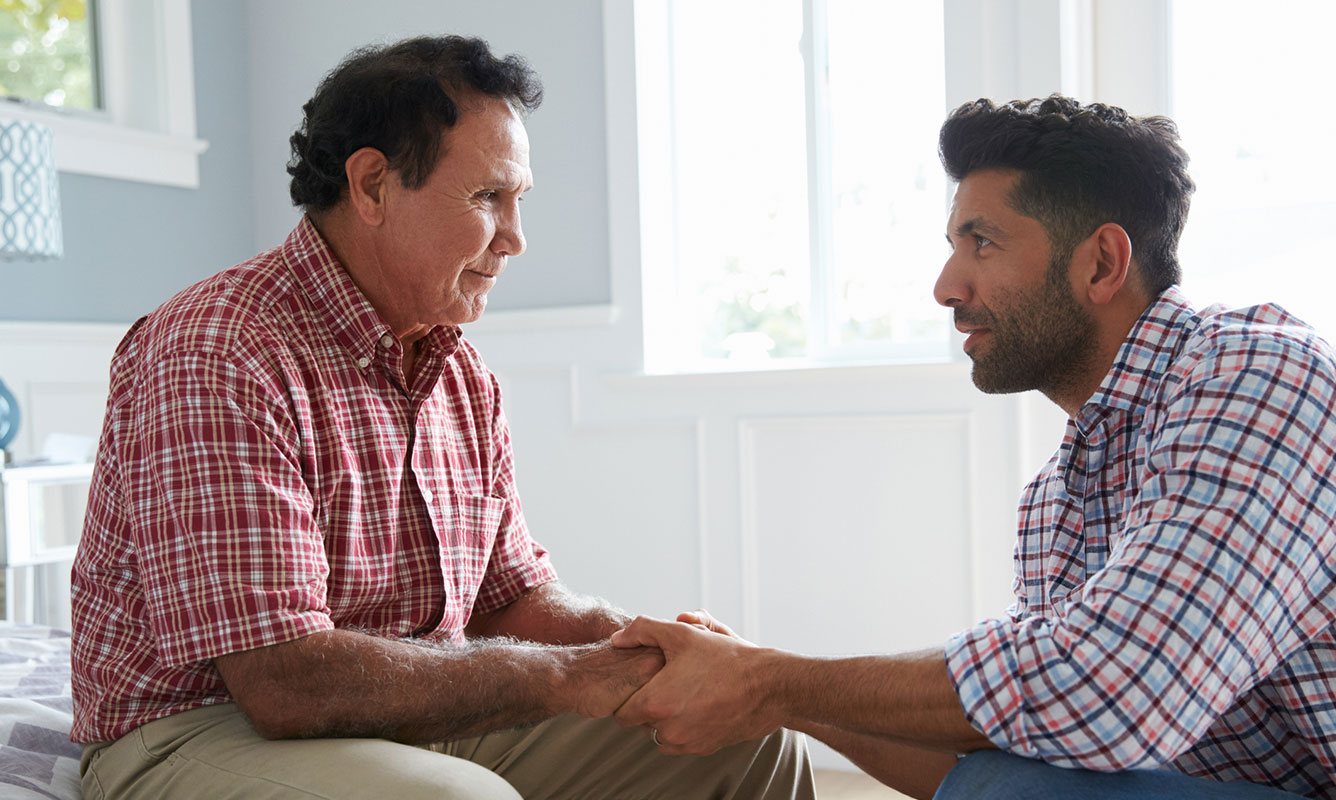 Son talks to his father at bedside helping with dementia issues