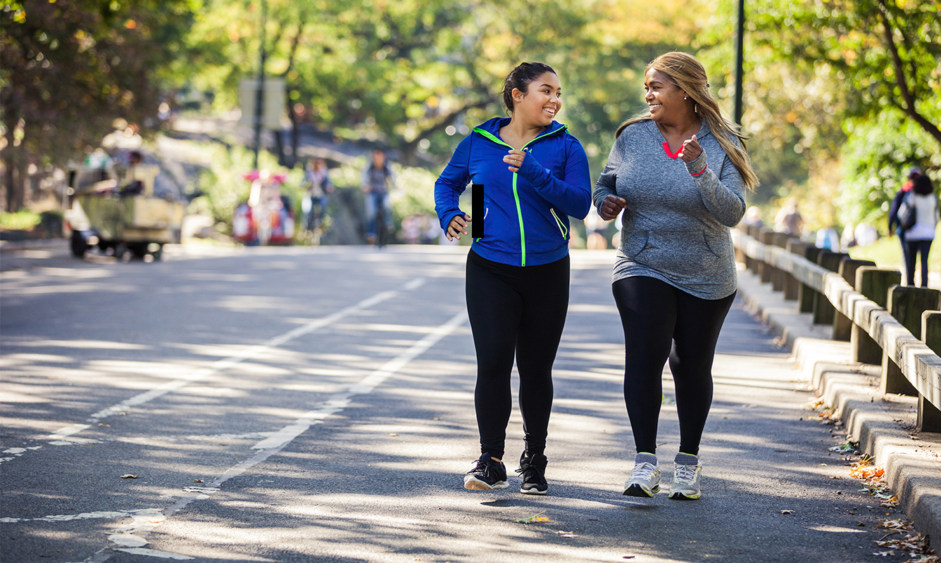 two women exercising, walking down the street together