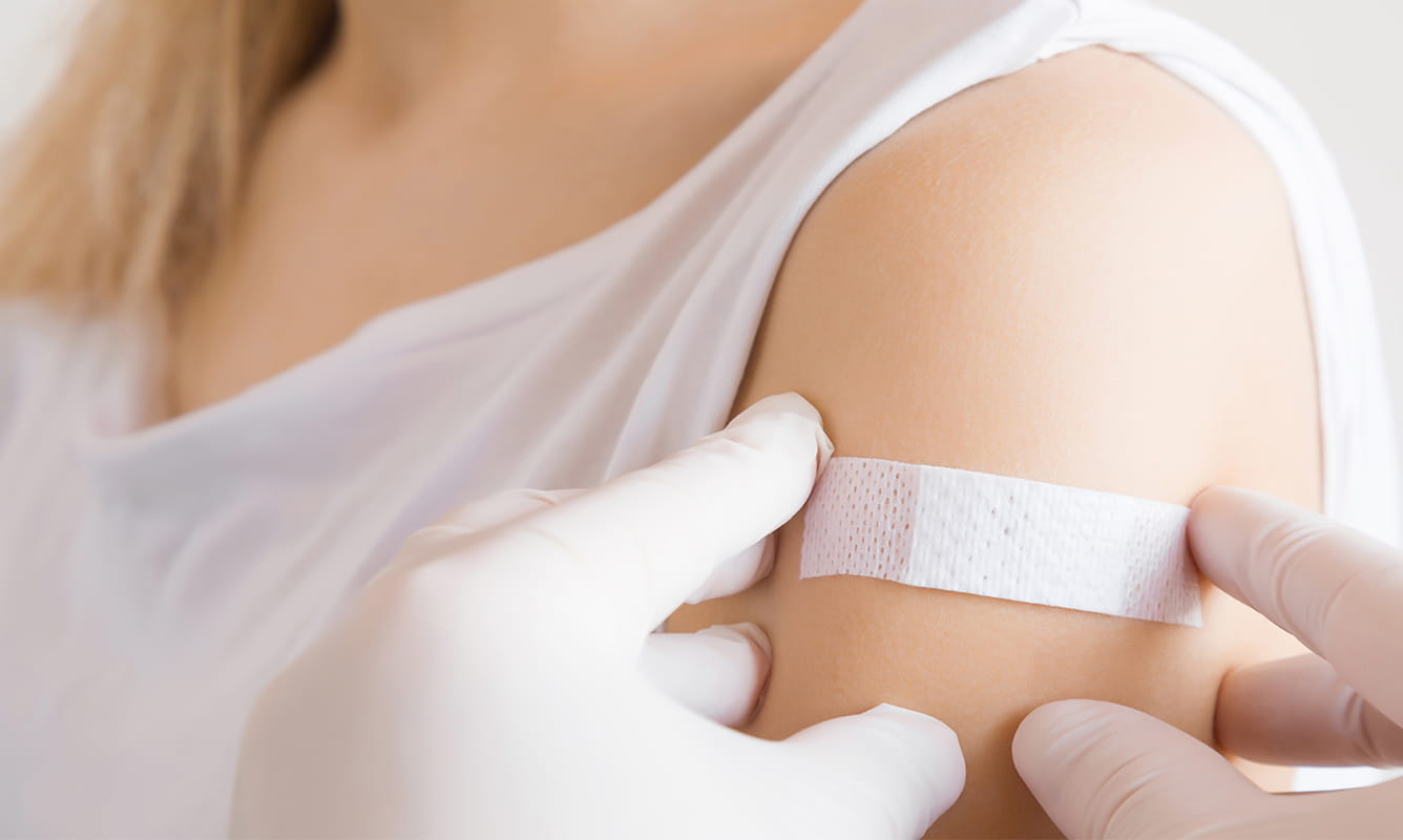 a doctor puts bandaid on female patient