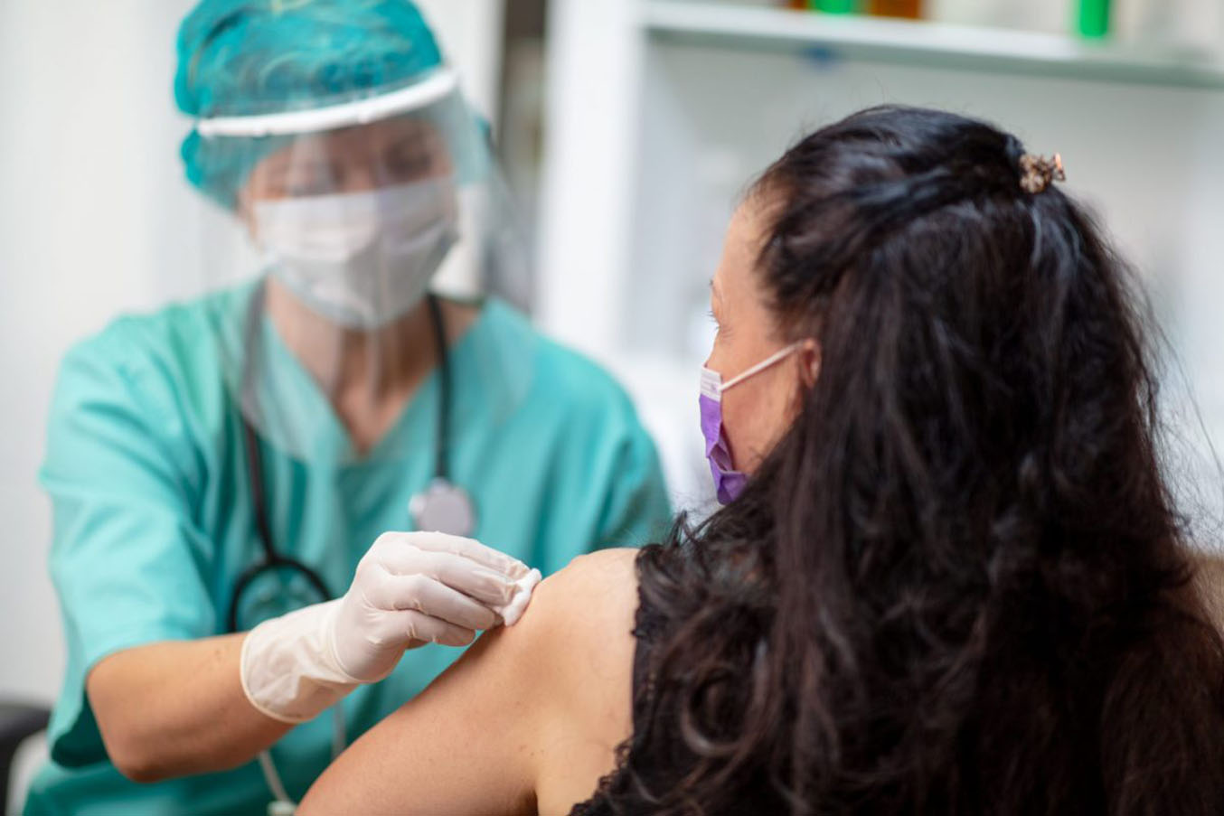 A health care provider gives a woman a shot