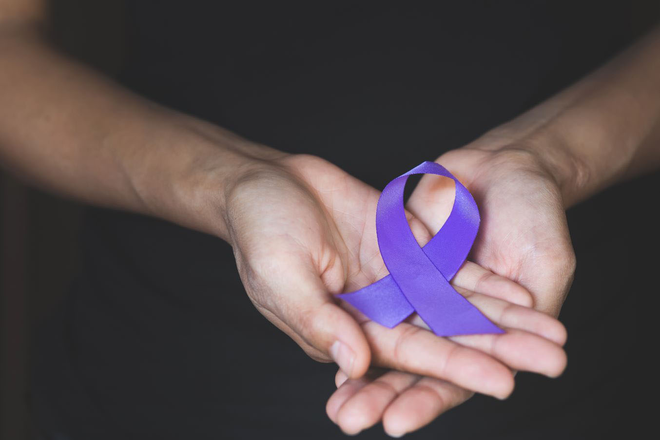 Hands holding a purple ribbon for domestic violence awareness month
