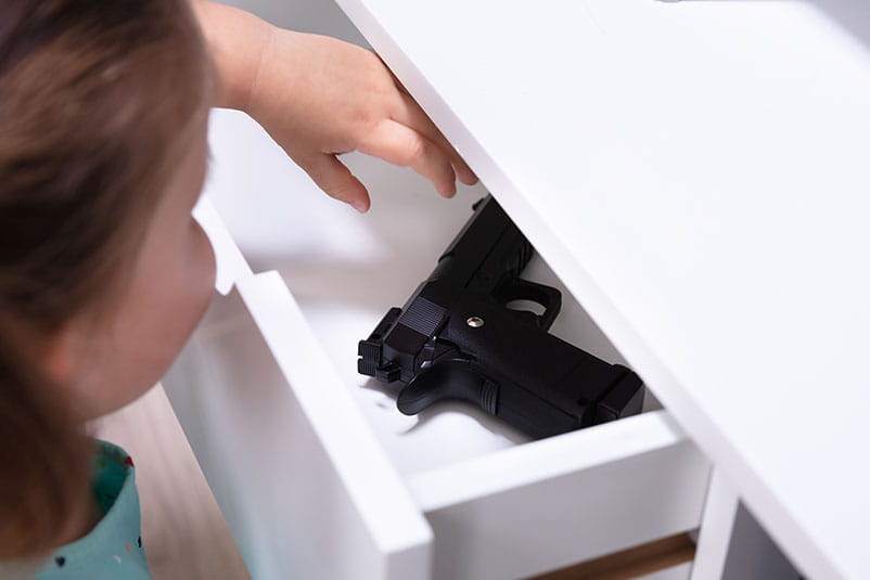 Closeup of a young girl reaching into a drawer for a gun.