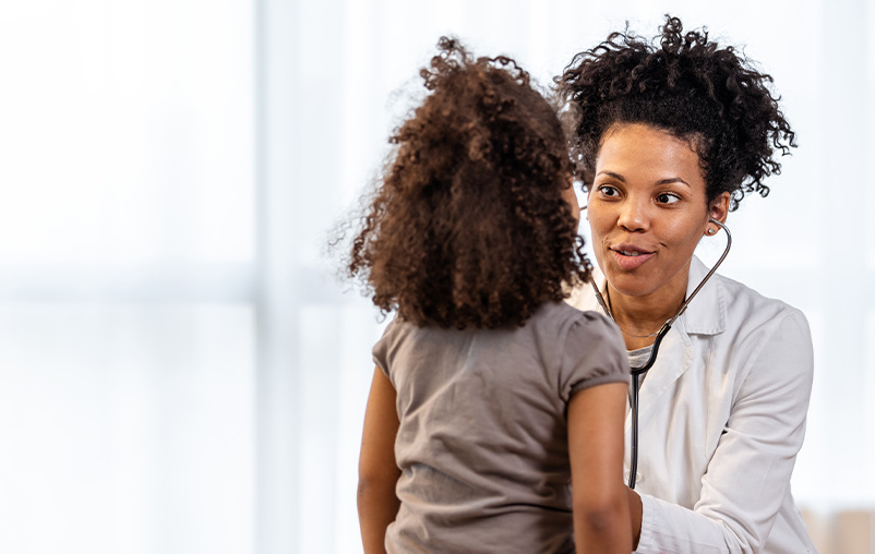 A female doctor speaks with a young girl.