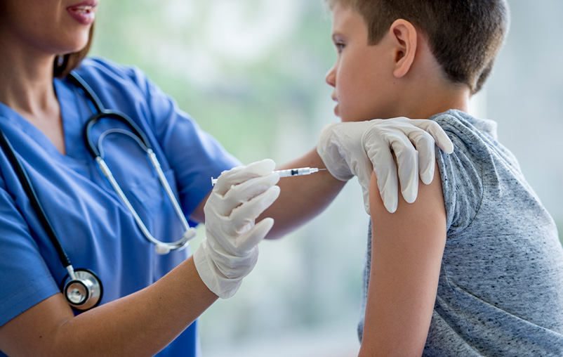 Young boy getting a flu shot from a health care provider.