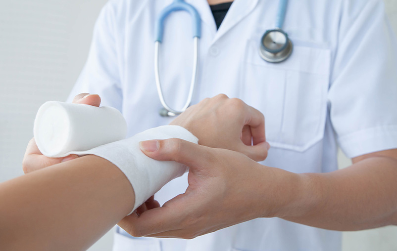 A medical provider wraps a bandage around a patient's arm.