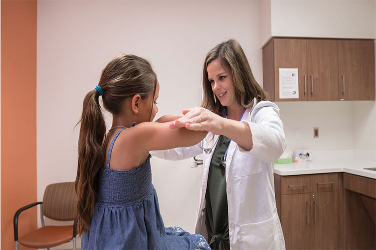 A Doctor checking a child's shoulder mobility during their sports physical
