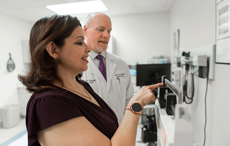 Dr. Kent Van Sickle, a bariatric surgeon, meets with female patient and checks her weight on a scale.