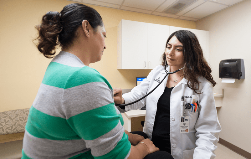 University Healthy physician performing routine check-up on female patient.