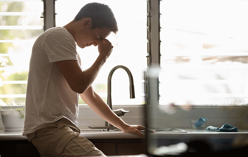 Young man touching temples with fingers as if suffering from a headache or dizziness which could be the result of high blood pressure. 