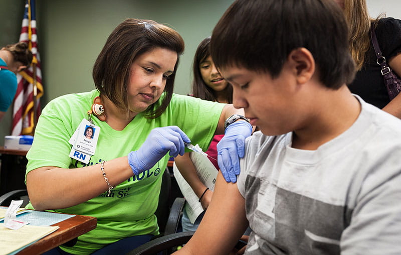 A University Health registered nurse providing immunization to child at a back-to-school immunization event, hosted at Texas Diabetes Institute.