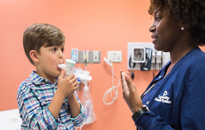 Pediatric patient practicing with inhaler at the University Health PediExpress