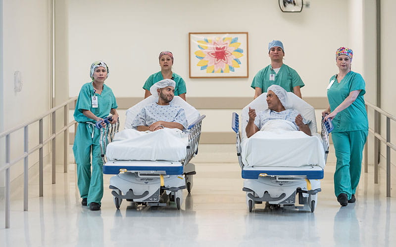University Health living organ donor and transplant recipient talking while being wheeled of by transplant team.