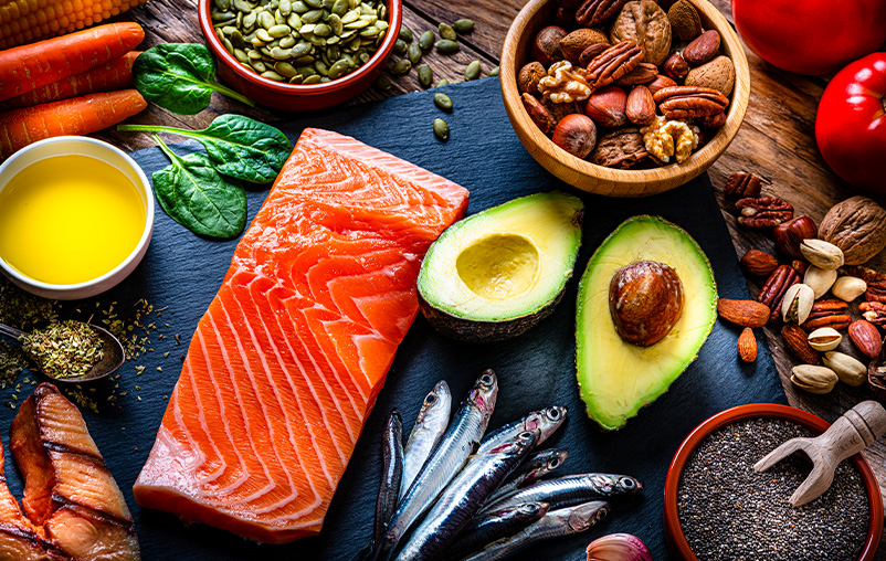 Healthy eating: high angle view of a group of food with high levels of Omega-3 fat. The composition includes salmon, sardines, avocado, extra virgin olive oil, and various nuts and seeds like pumpkin seeds, chis seeds, pecan, almonds, pistachio, walnuts and hazelnuts.
